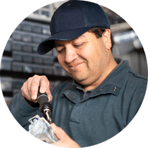 Maintenance man wearing a dark cap and using a screwdriver to fix something